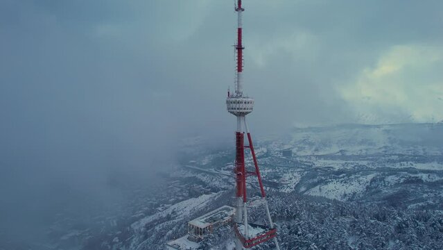 Transmit mast in the clouds above the snowy city