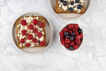 Whole grain bread toasts with cottage cheese and fresh raspberries ,blueberries and with flax seeds with cup of coffee , on a white background .Top view .Dieting concept .