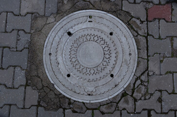 White sewer manhole on street.