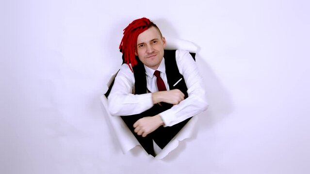 Close up of businessman hipster. Portrait man with red dreadlocks on his head throwing money banknotes, through a hole in the white wall in the studio