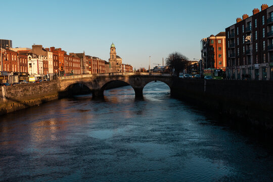 View of an old bridge above and various historical buildings in the Irish capital, springtime, sunset.