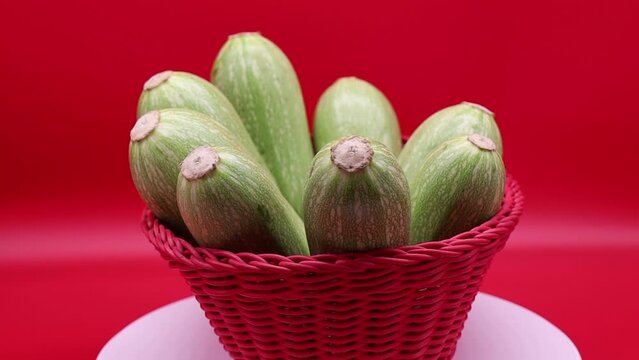 Rotating fresh zucchini isolated on red background. 