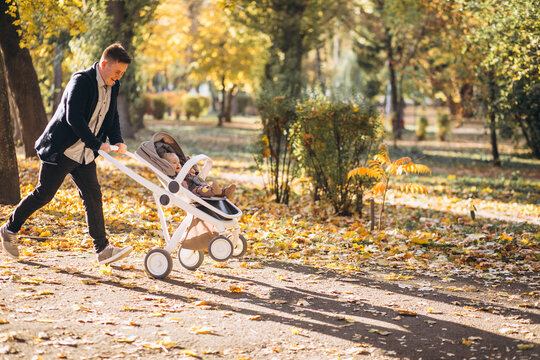 Young father walking with baby daughter in carriage in park