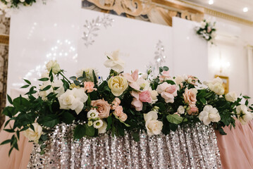Festive table newlyweds covered with a tablecloth and decorated with composition of flowers and greenery in the wedding banquet hall. Wedding party. Wedding decor.