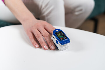 Close up of woman hand with oximeter on finger. Blood oxygen saturation metering.