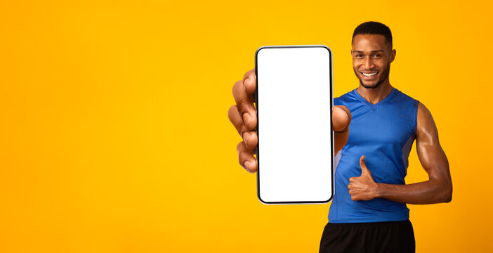 I recommend sports app. Muscular african american man holding smartphone with empty screen for mockup