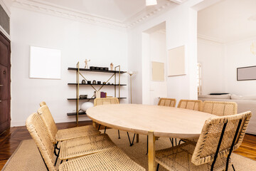Living room with oval wooden dining table, wicker chairs and wall shelf