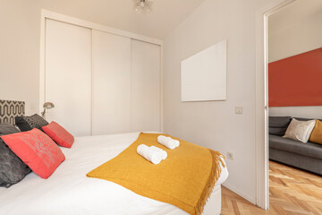 Bedroom with king-size bed, built-in wardrobe with white sliding doors, red and black cushions, and...