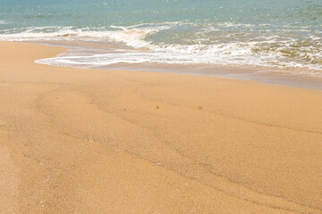 Fototapeta na wymiar Blue sea waves with foam on yellow sand beach.