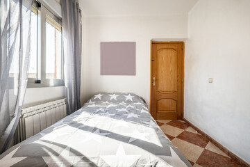 Fototapeta na wymiar Youth bedroom with gray quilt with stars, aluminum window with gray curtains, pine wood door and stoneware floors