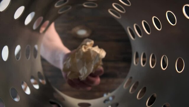 man hand picks up abandoned piece of paper in basket trash can or bin. Incorrect sorting of garbage, paper thrown out by mistake, returned to its place.