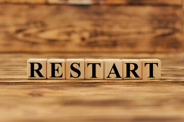 Wooden cubes with letters on a white table. The word is RESTART. White background.