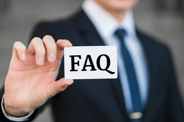 FAQ. Businessman in suit with a black tie showing or holding business card