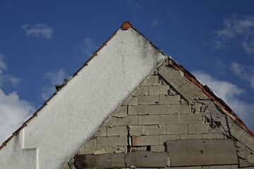 House wall with dirty plaster and naked brickwork after demolition of one house half, concept:...