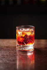 Crystal glass of classic negroni cocktail with ice on dark background
