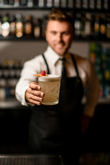 selective focus on glass with foamy cocktail decorated with orange slice and a raspberry in male hand