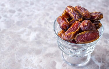 Dried date fruits in bowl on marble background, space for text