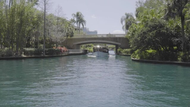 A slow moving passenger boat travels underneath a bridge