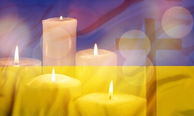 A burning candle on ukraine flag background
