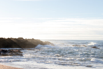 waves hitting rocks on the shore and beach