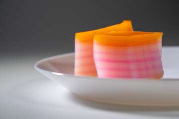 Nyonya delights dessert “Kuih Lapis” (Steamed Layer cake desserts) on white plate and isolated grey background.