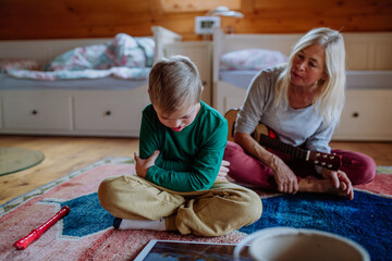 Boy with Down syndrome sitting on floor and playing with his grandmother at home