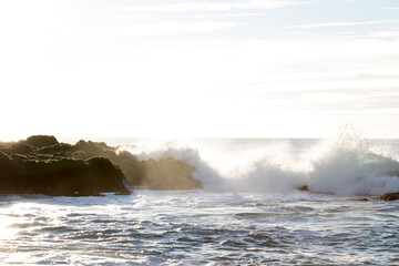 waves hitting rocks on the shore and beach