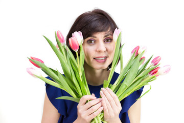 An adult brunette woman looks out from behind a bouquet.