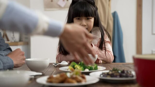 selective focus of amazed Asian daughter holding face with anticipation her mother is putting on delicious dish on dinner table at home