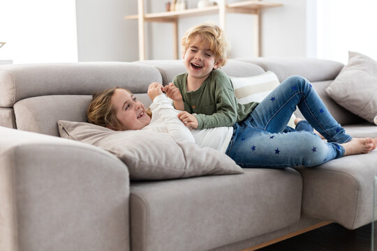 Cheerful siblings playing on sofa