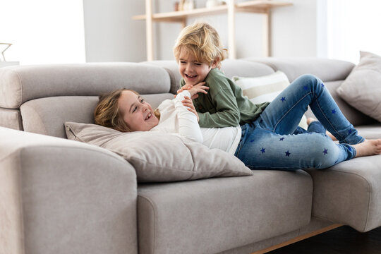 Cheerful siblings playing on sofa