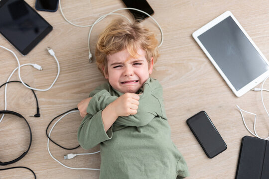 Crying boy amidst various gadgets