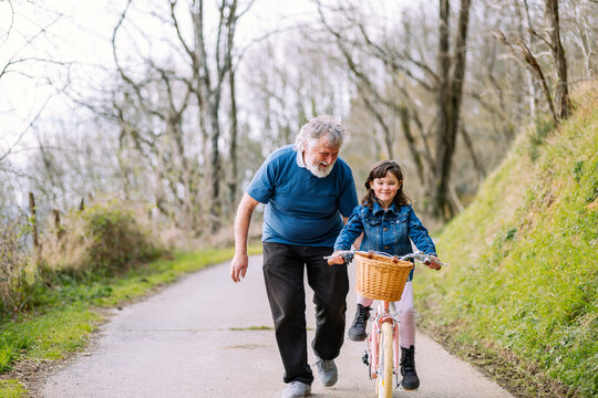 Grandfather teaching girl riding bicycle in countryside