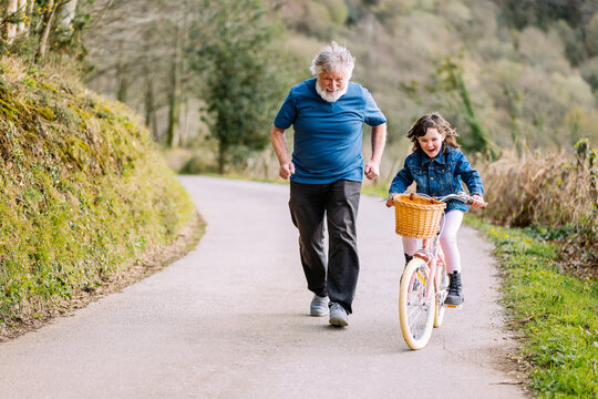 Grandfather running with granddaughter riding bicycle