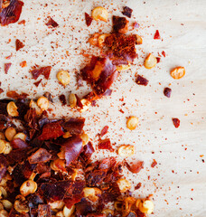 Dried red chili flakes on raw wooden surface
