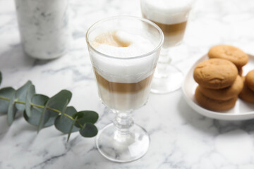 Delicious latte macchiato and tasty cookies on white marble table