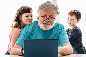 Grandfather browsing laptop with kids
