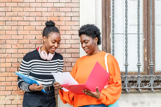 Happy black women with folders in city