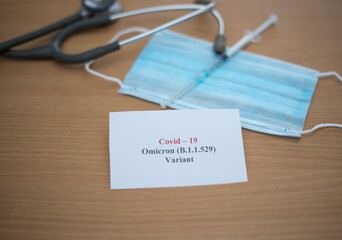 Medical facemask with a stethoscope and a syringe needle on the table - COVID Omicron variant