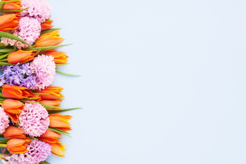 Bright orange tulips and pink hyacinths on a light blue background. Mothers Day, birthday concept.