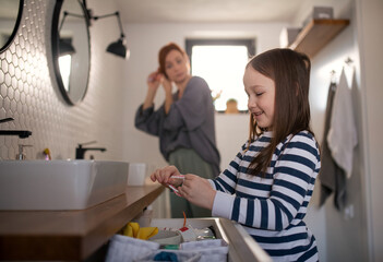 Mother with little daughter in bathroom, morning routine concept.