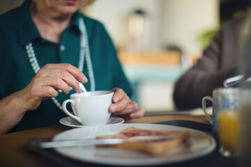 Close-up of senior woman enjoying breakfast in nursing home care center.