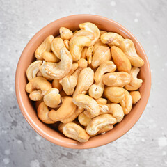 Cashew nuts in a bowl. On a stone background. Top view. Free space for text.