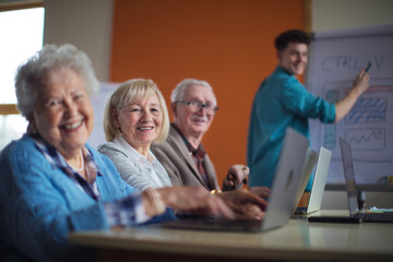 Obraz premium Senior group in retirement home with young instructor learning together in computer class