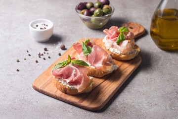 Bruschetta with prosciutto, basil, olives, spices and herbs. Appetizers.