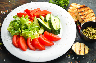 Assorted vegetables in a plate. Slicing fresh vegetables: cucumber, tomato, pepper. Restaurant menu. Top view.