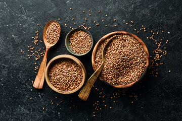 Organic buckwheat groats in a wooden bowl. on a stone background. Healthy food.