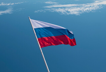 Waving Russian flag against a blue sky with clouds.