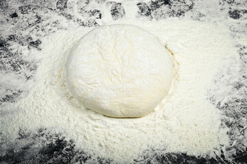 Female hands holding a piece of dough for baking bread. Black cooking background.