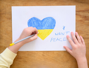 Ukrainian girl kid hands protesting against war conflict and drawing message text "I want peace". Painted heart with Ukrainian colours flag. No war, stop war, russian aggression, crisis, peace, 